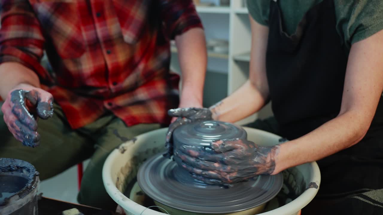 Couple working together on a pottery wheel