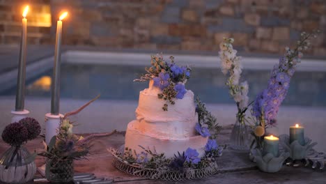 rustic-wedding-cake-with-wild-boho-flowers-by-the-pool,-evening-wedding-reception