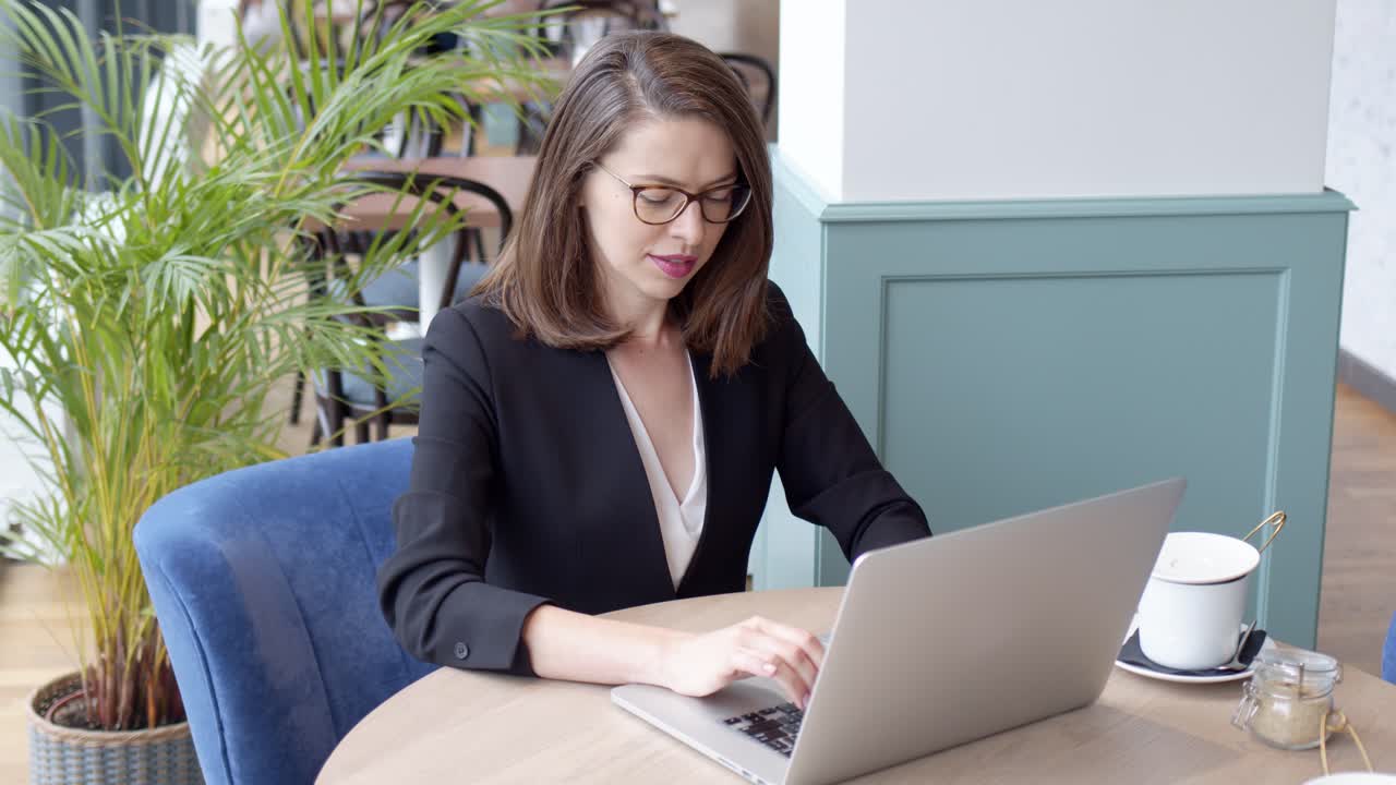 Giovane donna d'affari felice che usa un computer portatile in un caffè