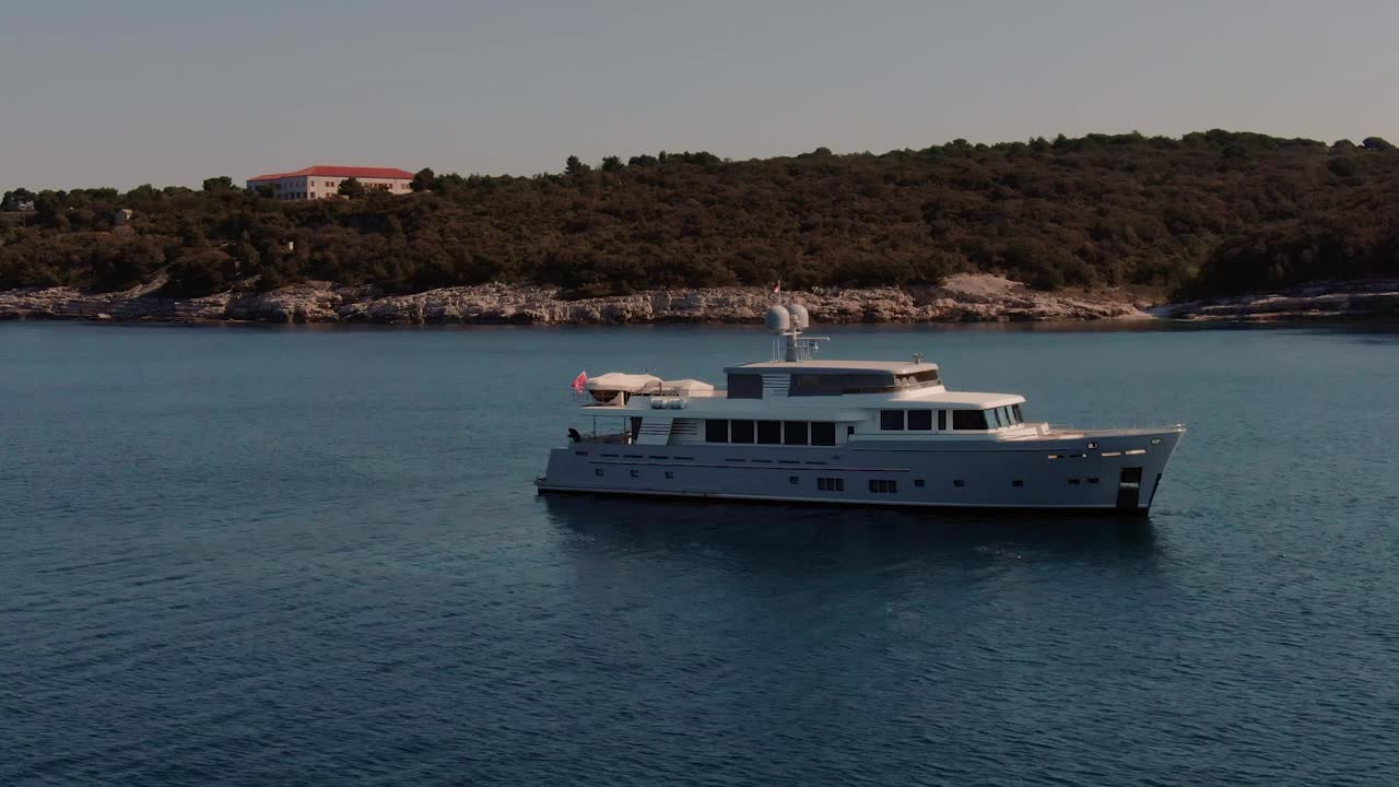 Tracking shot white yacht anchored in the bay, at sunset