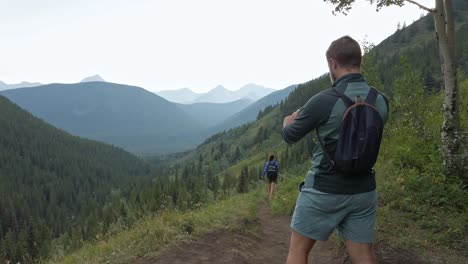 hikers photographing walking downhill on a trail in high altitude rockies kananaskis alberta canada