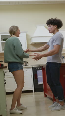 video vertical de una pareja feliz y diversa bailando en casa