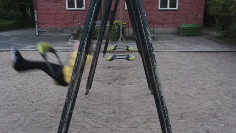 imágenes de una mujer con un suéter amarillo usando un columpio en el patio de una escuela