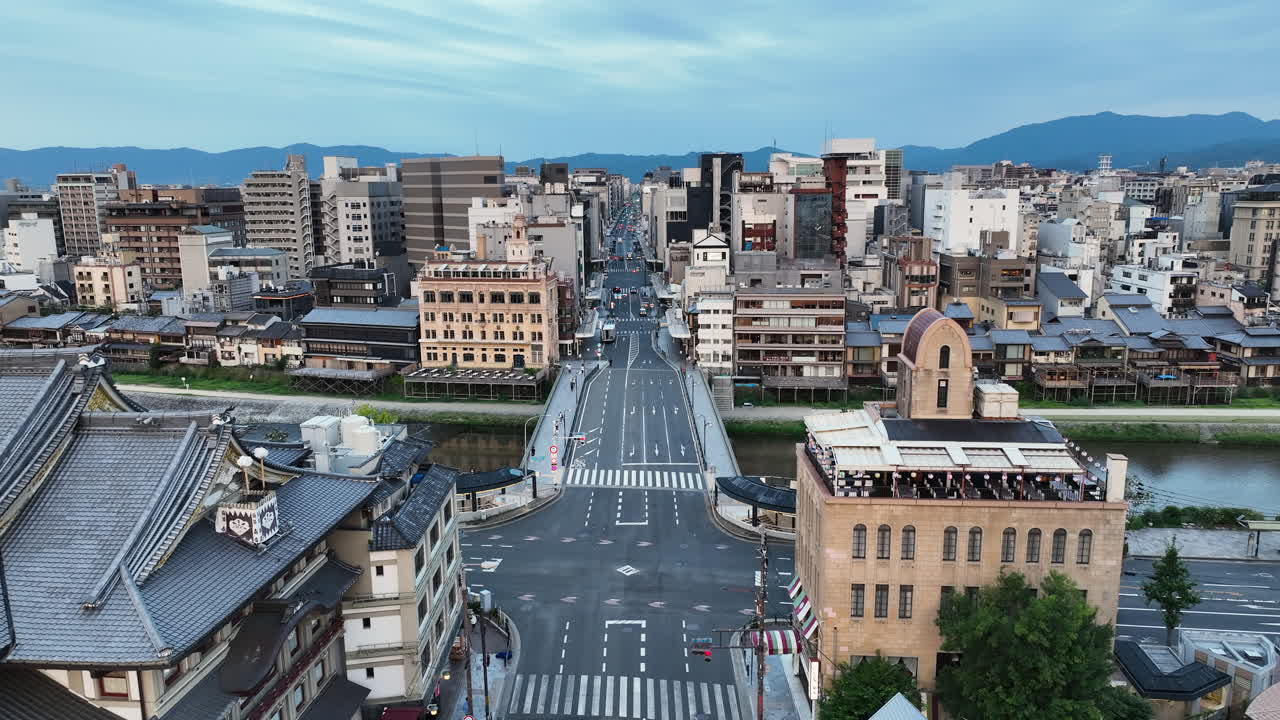 Birds Flying Over The Street, Shijo Bridge Over Kamo River And Residential Buildings In Kyoto, Japan. - aerial shot