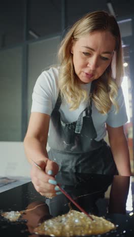 woman artist painting on glass with gold leaf