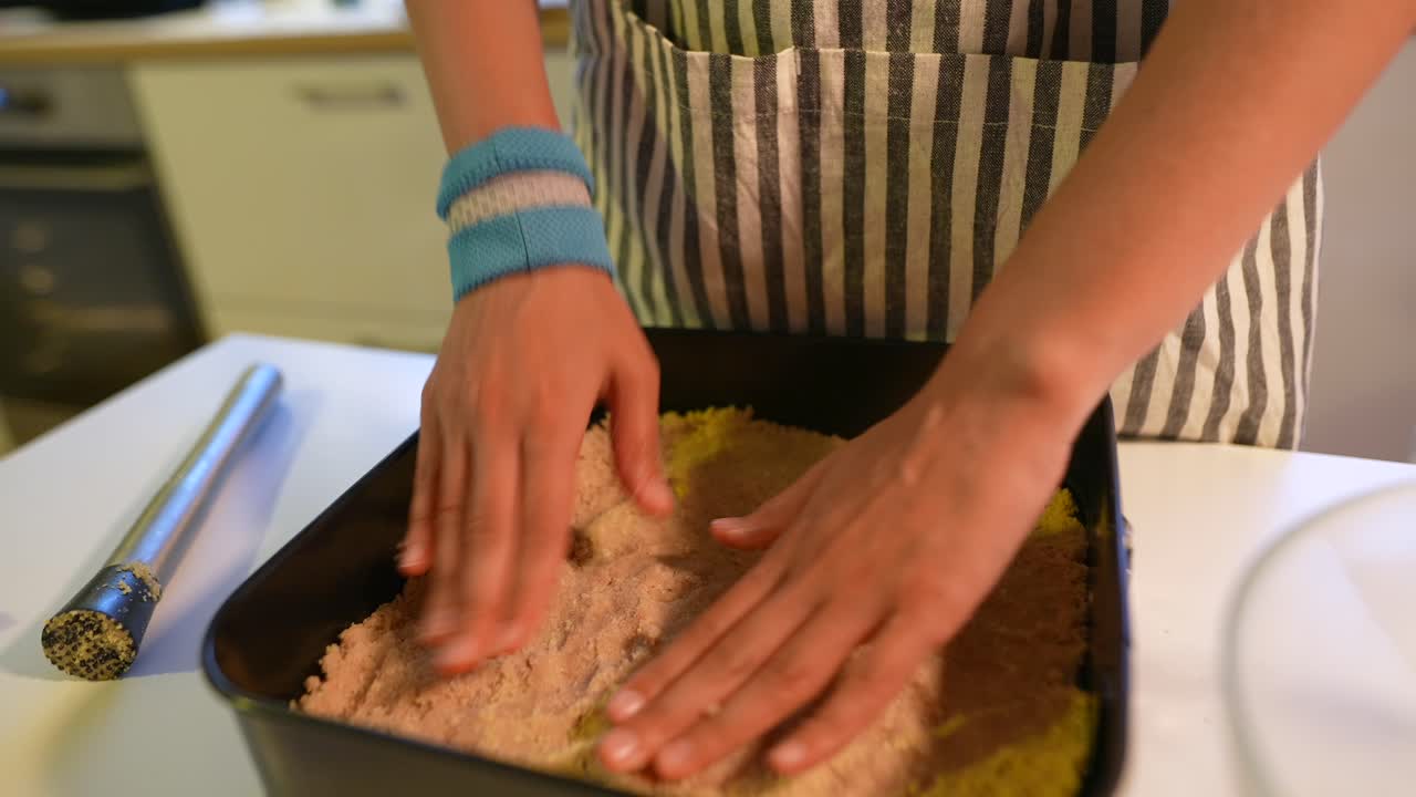 Tangan menekan kulit remah ke dalam loyang panggang di dapur