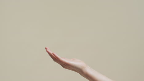 mano de mujer asiática en fondo beige con espacio de copia, cámara lenta