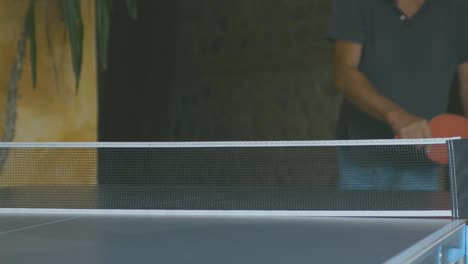 slow motion of a boy hitting a backhand ball during a game of ping pong in a corporate team building moment