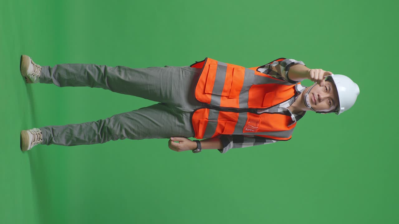 Full Body Of Asian Male Engineer With Safety Helmet Smiling And Touching His Chest Then Pointing At You While Standing In The Green Screen Background Studio