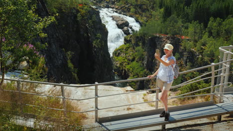 a woman looks at the majestic waterfall of woringsfossen in norway impressive beauty of scandinavian