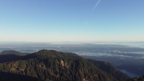 Increíble-Vista-Aérea-De-Vancouver-Canadá-Bc-Desde-La-Montaña-De-La-Corona-Con-árboles-En-La-Cima-De-La-Montaña-Y-Una-Turbina-De-Viento-Solitaria---Empujando-Un-Dron-Disparado-4k