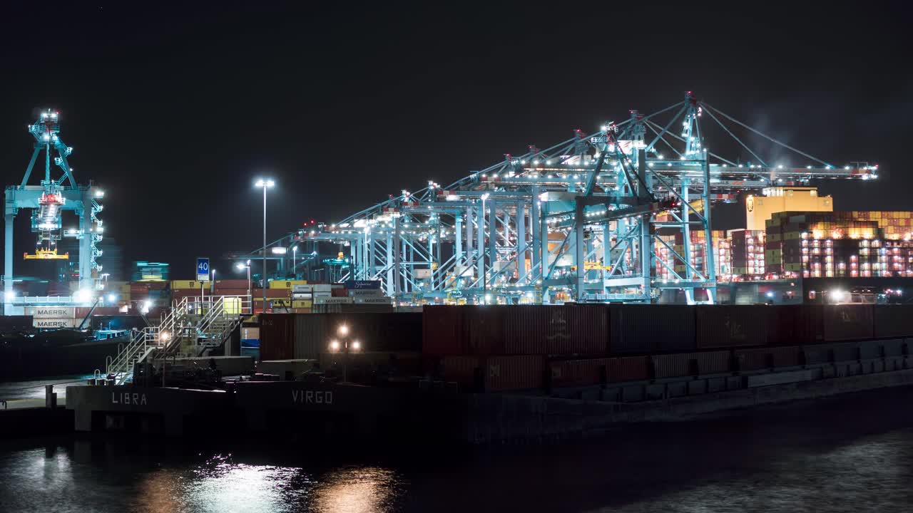 Busy port cranes terminal loading containers onto ship at night, time lapse