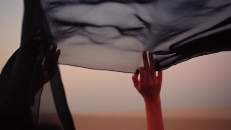 black scarf held up while the wind blowing it, windy desert, united arab emirates, fossil dunes