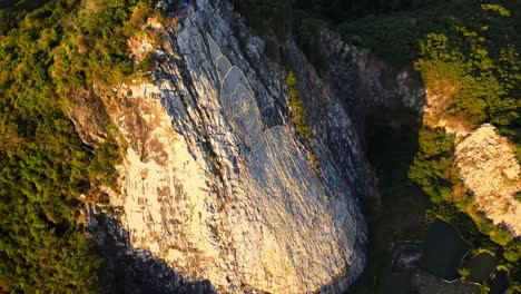 4K-Drohne-Fliegt-Um-Geschnitztes-Buddha-Bild-Aus-Gold-Auf-Einem-Felsen-In-Khao-Chee-Chan,-Pattaya,-Thailand