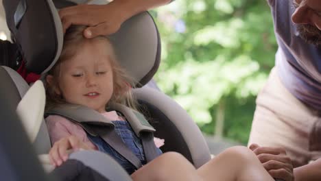 video of father securing daughter to a baby car seat.