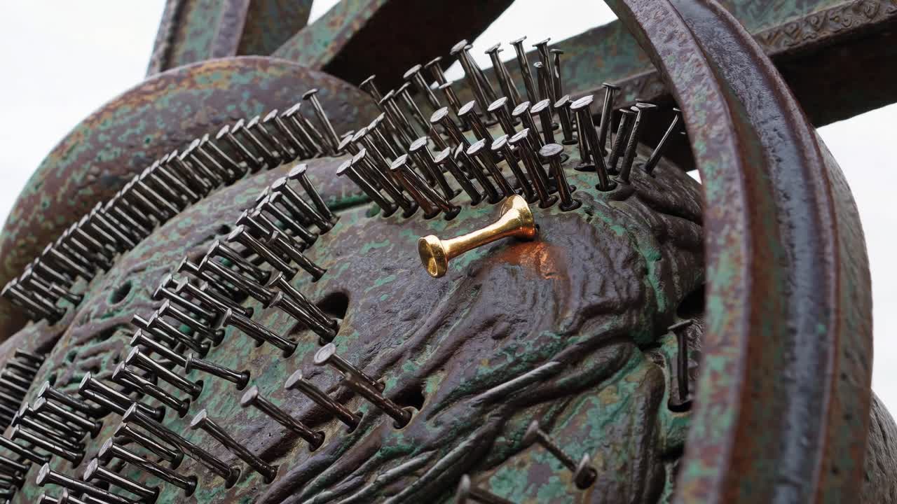 Close-up of a Metal Sculpture with Nails and a Gold Pin