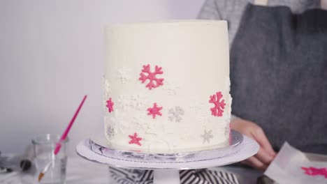 decorating round funfetti cake with pink and white fondant snowflakes.