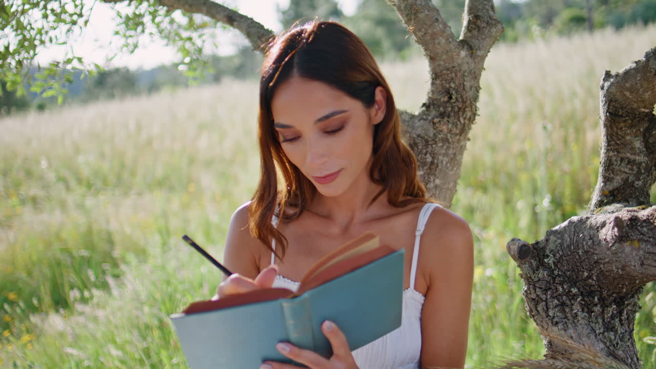 Romantic lady holding book putting marks in summer garden closeup