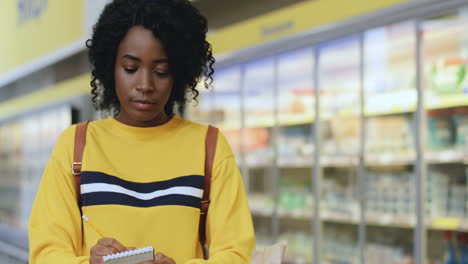 portrait of a beautiful girl taking notes in a supermarket looking at the camera and smiling