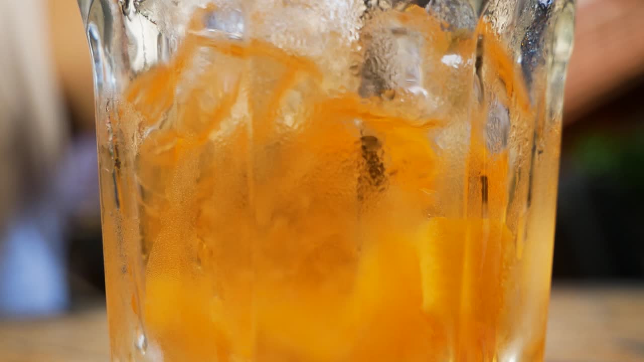 Donna che gusta un cocktail all'arancia, mescolando con una cannuccia al ristorante