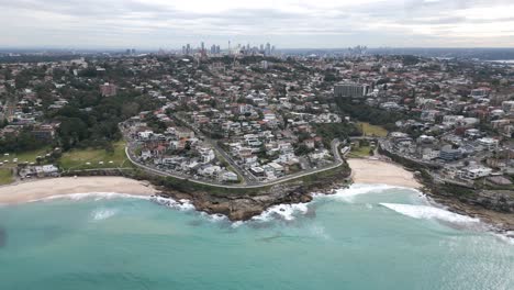 Die-Zurückgezogene-Luftaufnahme-Des-Strandes-Von-Malabar-Zeigt-Die-Küste-Von-Sydney-Und-Die-Stadt-CBD-Am-Horizont