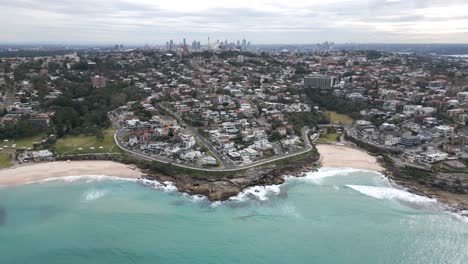 aerial pull back shot of malabar beach reveals the sydney coastline and city cbd in the horizon