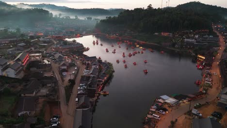 aerial dolly push in above ban rak thai village in thailand, mountains, lakes, and tea plantations surround homes and boats in water