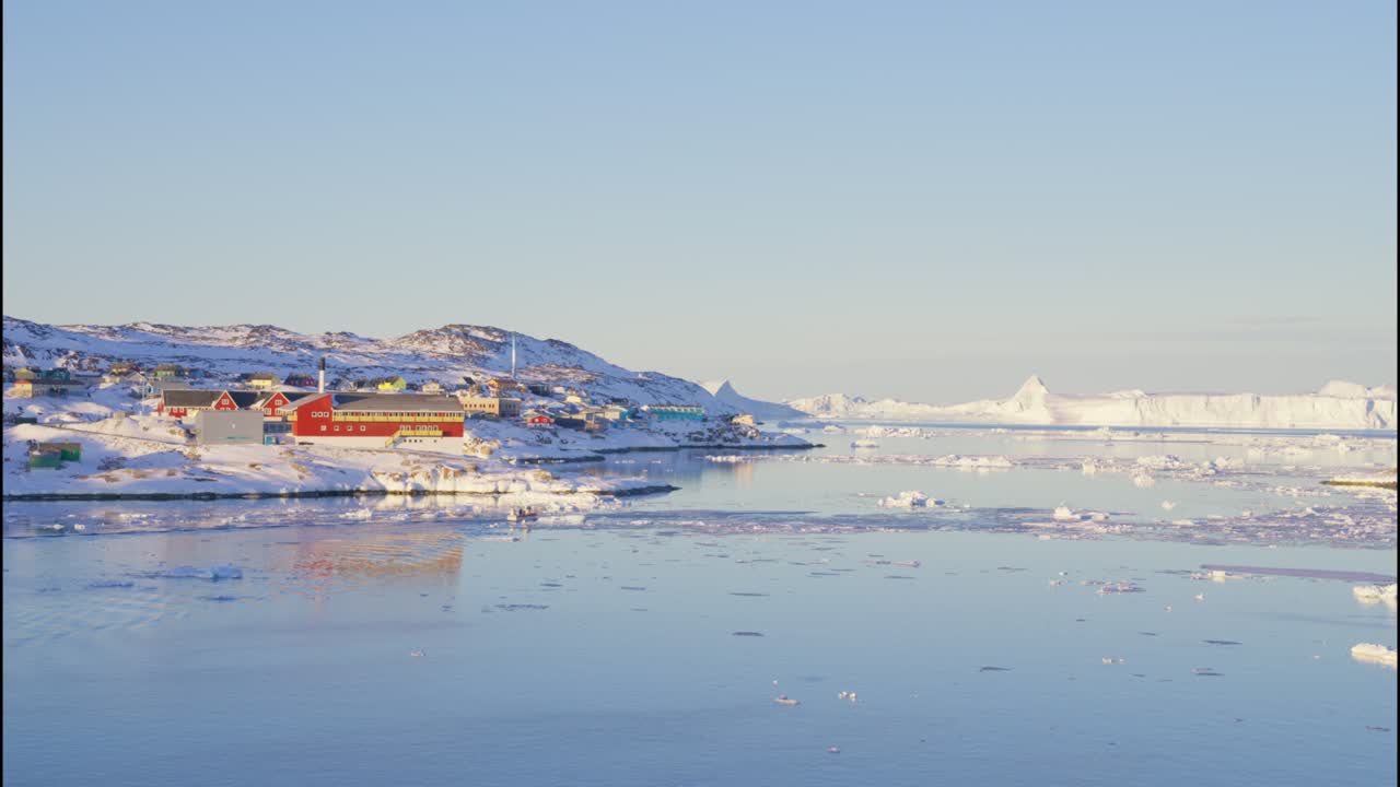 얼음과 눈으로 바다에서 배와 함께 해안선에 빛 도시