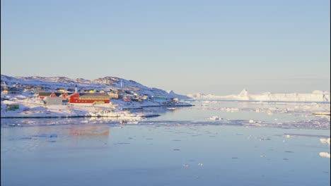 ciudad iluminada por el sol en la costa con un barco en el mar con hielo y nieve