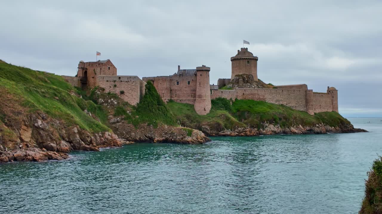 Panning shot of Fort la Latte on a cliff, with the sea and green landscape in Brittany, France.