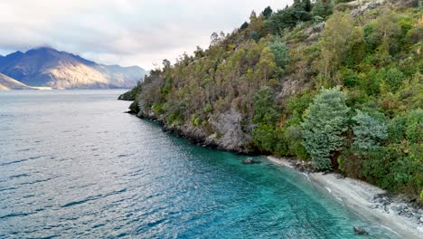 aerial footage captures lake wakatipu's serene waters and lush shoreline in queenstown, new zealand, under soft daylight