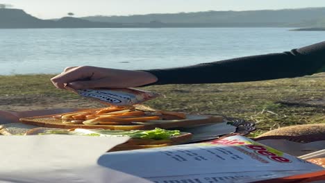 vertical footage, with friends camping and making breakfast of bread, sandwiches, sausages with a view of the clean sermo reservoir.
