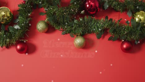 Animation-of-merry-christmas-over-baubles-and-fir-tree-on-red-surface