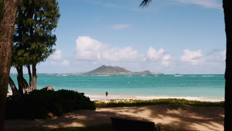 Drohnenschuss,-Der-Durch-Bäume-Am-Strand-Von-Hawaii-In-Richtung-Insel-Im-Tiefblauen-Wasser-Schiebt