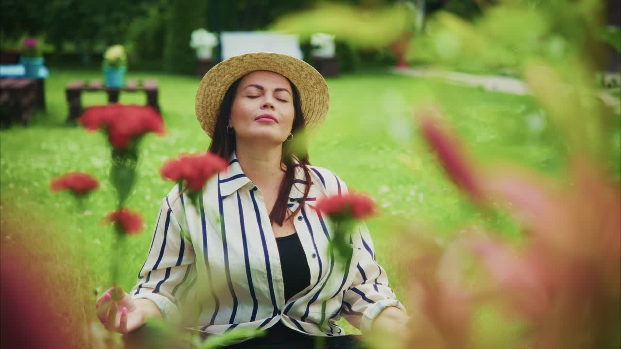 Woman enjoying tranquility in a garden surrounded by vibrant flowers and greenery