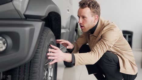 satisfied young man appreciates the wheel of a car