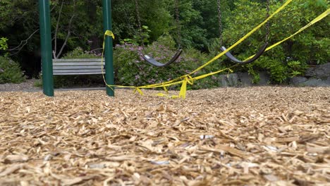 Leere-Schaukel,-Die-Langsam-Auf-Geschlossenem-Spielplatz-Schwingt,-Der-Mit-Warnband-Markiert-Ist