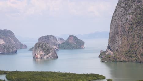 aerial footage captures the serene beauty of phang nga bay's limestone islands under clear skies, showcasing lush greenery and tranquil waters