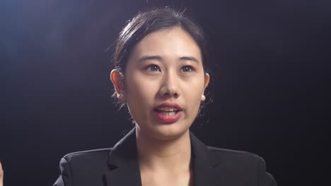 close up of asian speaker woman in business suit speaking in the black screen studio