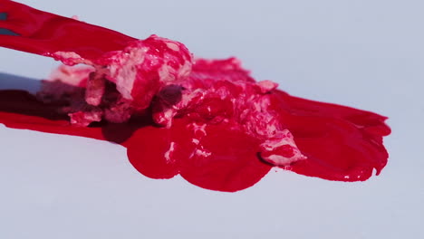 una espátula se usa para mezclar pintura roja y rosa