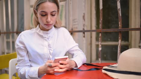 Slow-Motion:Attractive-young-beautiful-girl-uses-smart-phone-while-sitting-at-a-cafe-outside