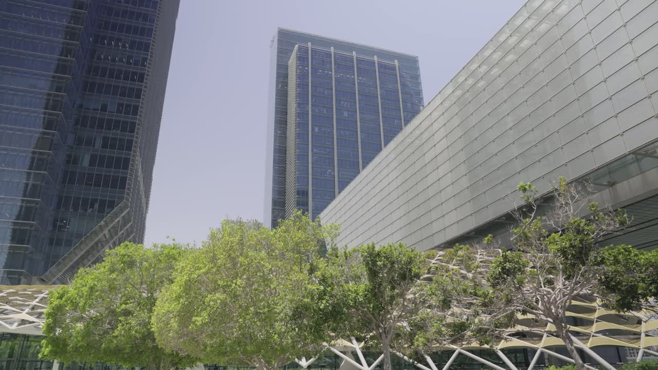Filmagem cinematográfica diurna da arquitetura do ADGM em Abu Dhabi, destacando linhas limpas e design urbano contemporâneo