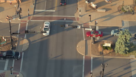 Aerial-of-main-street-with-a-tilt-down-to-follow-a-white-car-driving-down-the-street