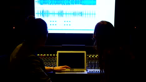 audio engineers using laptop while mixing sound