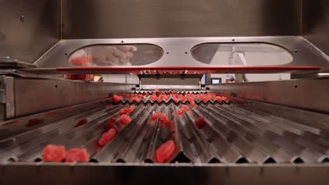 las vitaminas gomosas rojas se extienden para deslizarse por la rejilla de metal corrugado - fabricación