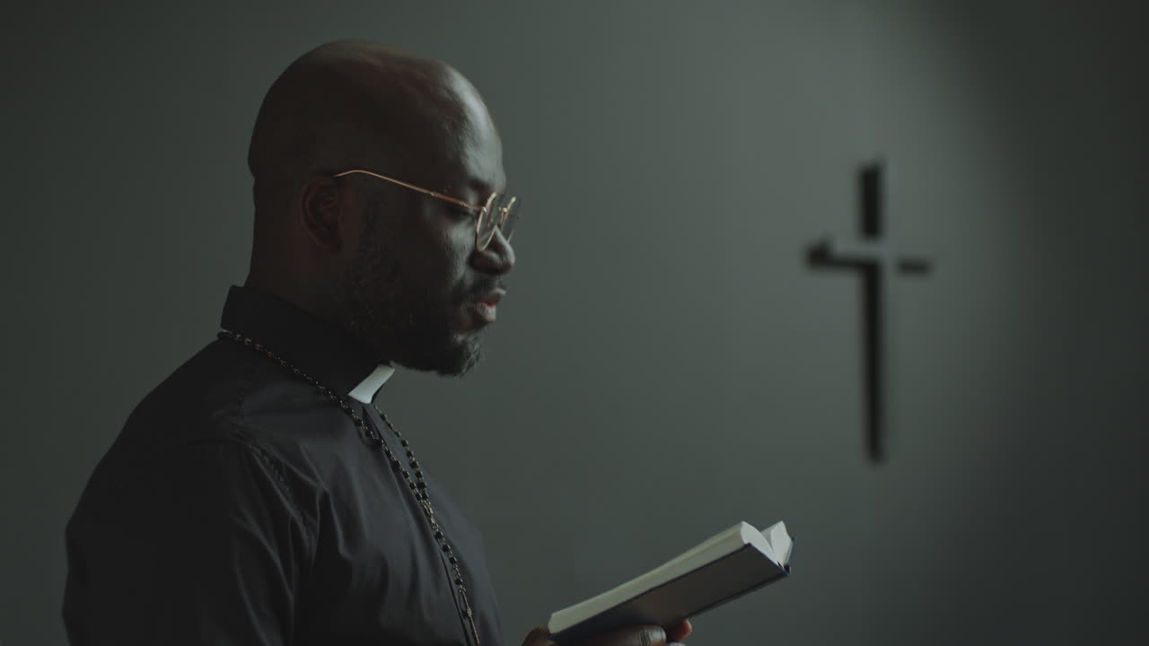 Afroamerický kněz čte Bibli v kostele během liturgické bohoslužby