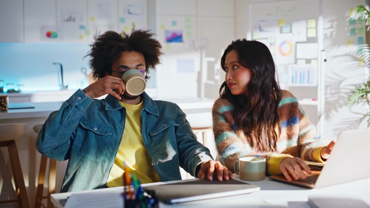 Coworker team drinking coffee working laptop home office. Multiracial startup.
