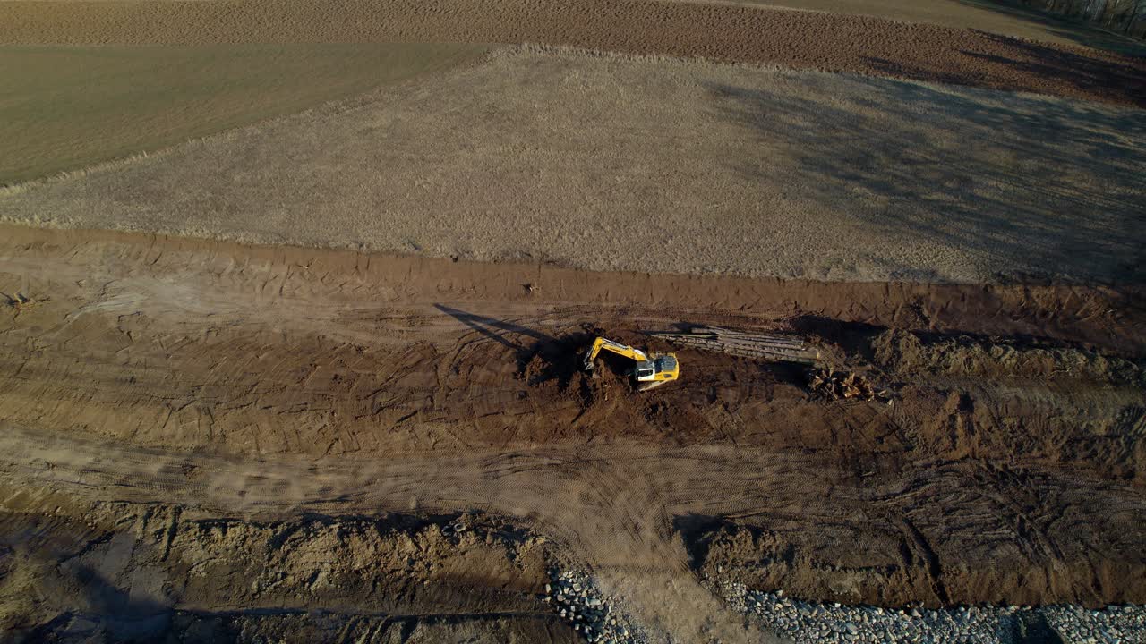 Aerial overview of a yellow excavator working on a construction site at daytime
