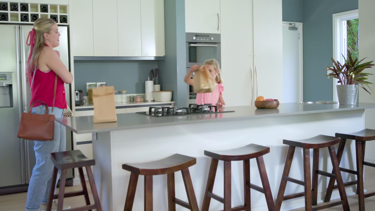Tür öffnet sich, Mutter und Tochter tragen Papiertüten und einen Netzbeutel, packen Lebensmittel für das Abendessen aus.