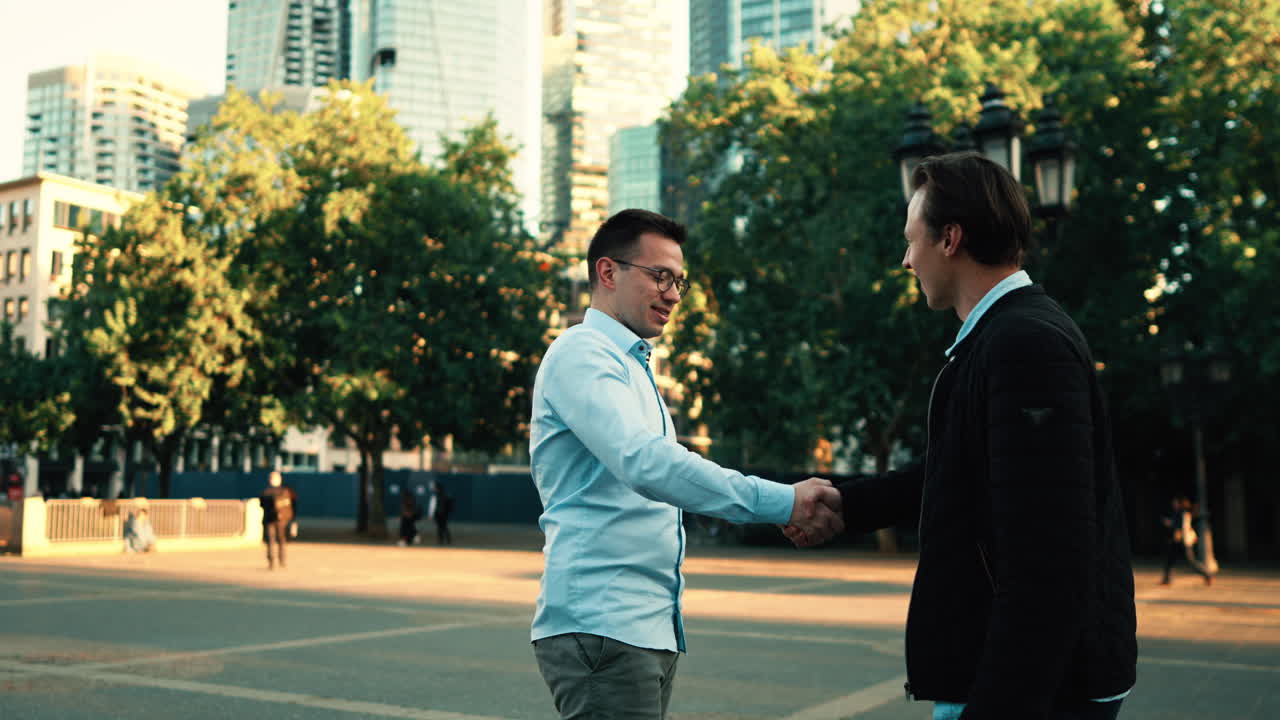 Two young professionals greet each other with a handshake near Frankfurt’s financial center. A blend of nature and skyscrapers sets the stage for modern business, consulting, or partnership themes.